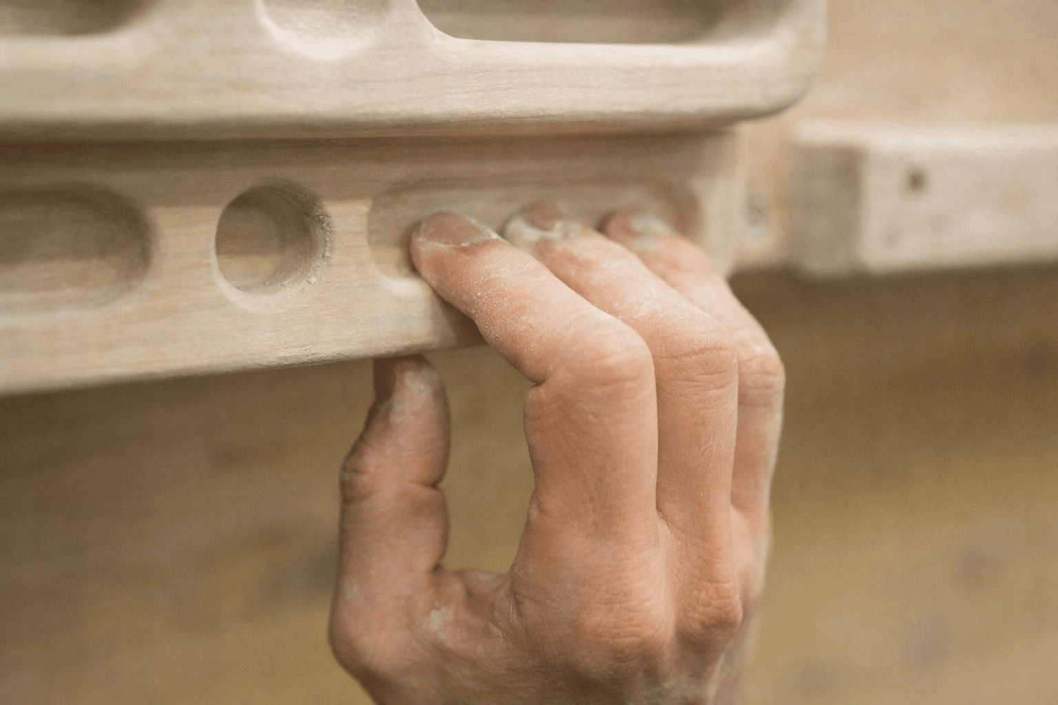 Close-up of a climber's hand on a fingerboard during a finger strength training session.