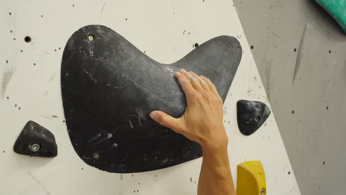 Climber loading a small edge with chalked fingers.