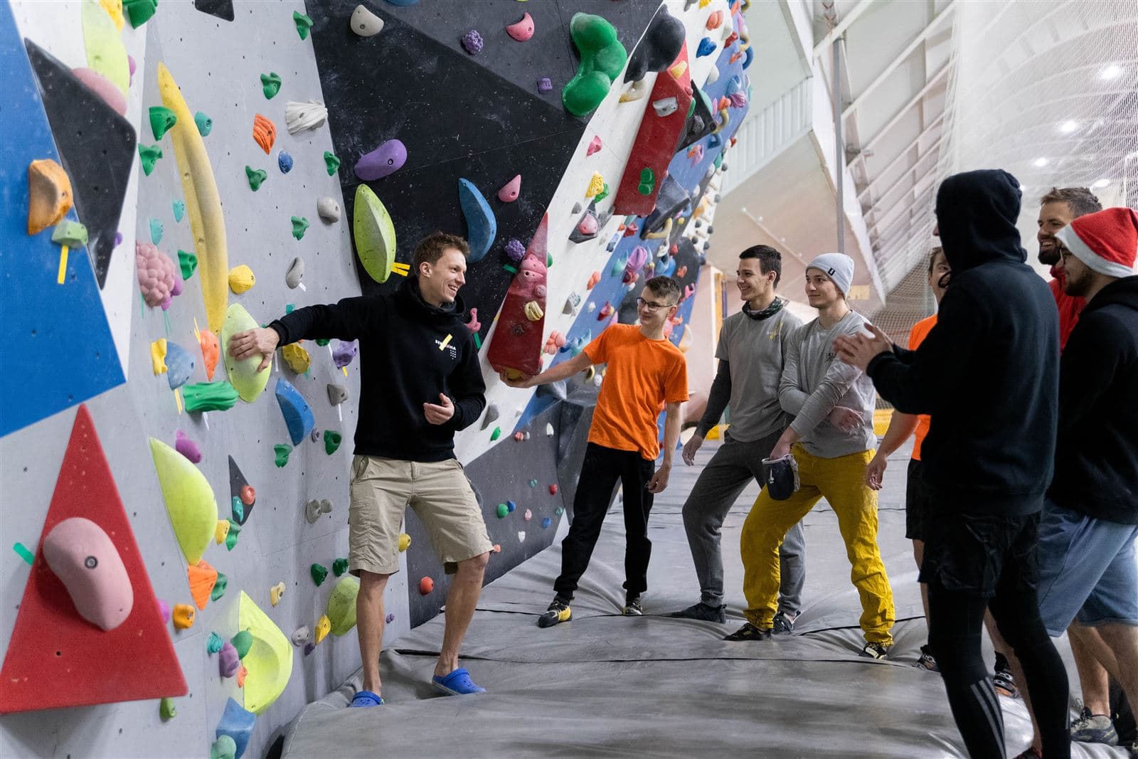 Alex Voit coaching a group of climbers at an indoor bouldering wall