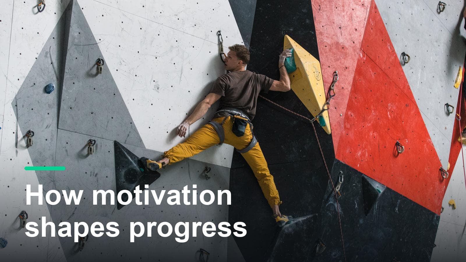 Climber bridged wide on an indoor lead wall, with the words How motivation shapes progress.