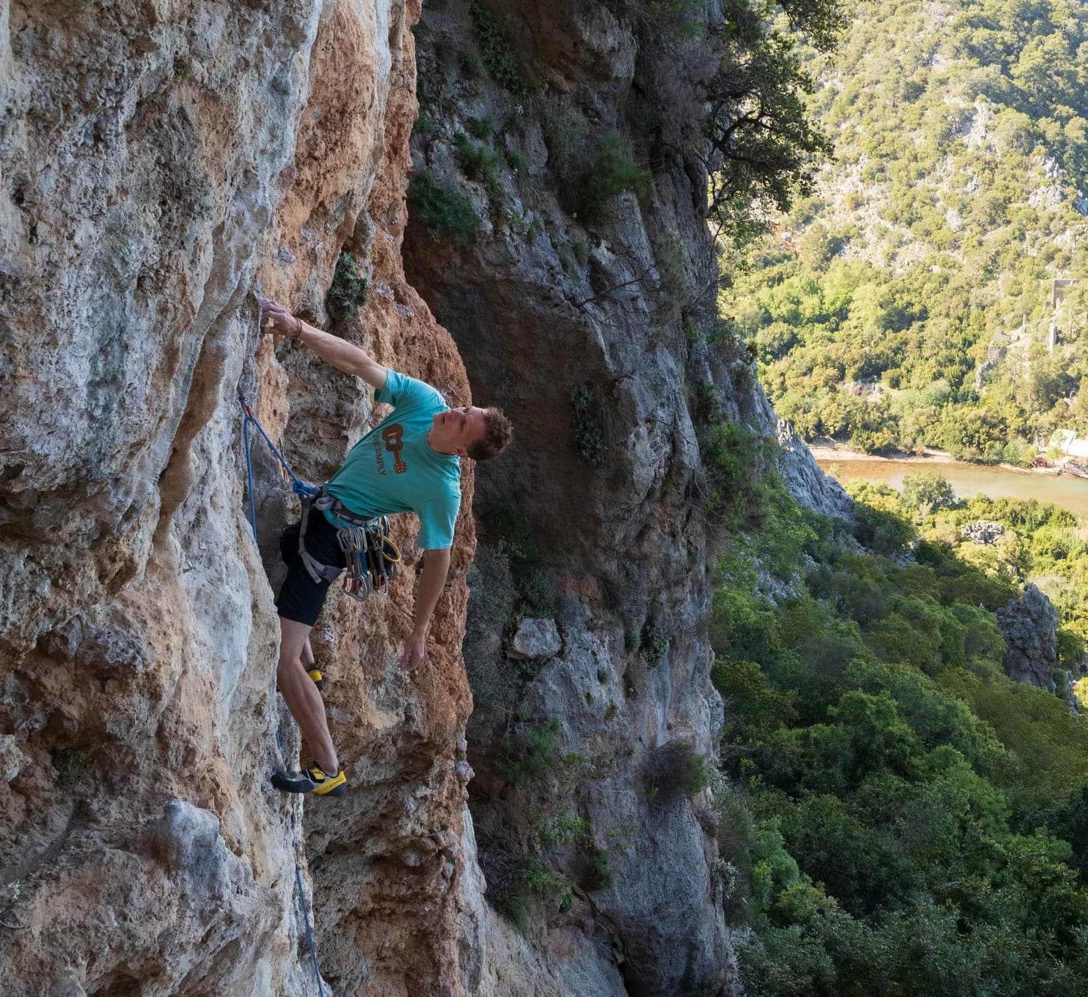 A climber on a limestone cliff above the sea