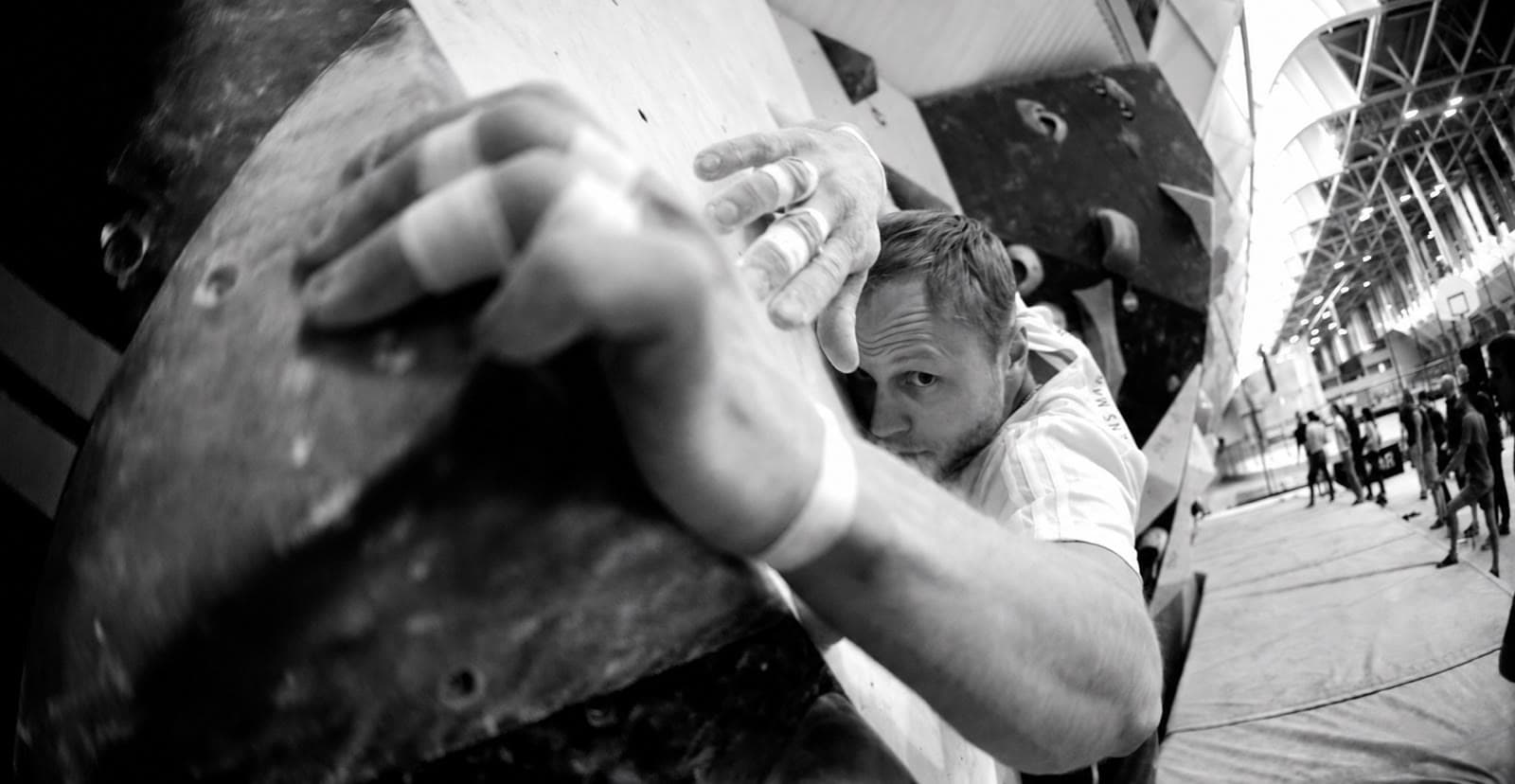 Ein Boulderer mit getapten Fingern greift nach einem Griff