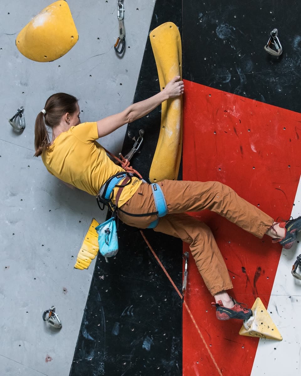 Eine Person steigt in einer Kletterhalle eine Route vor